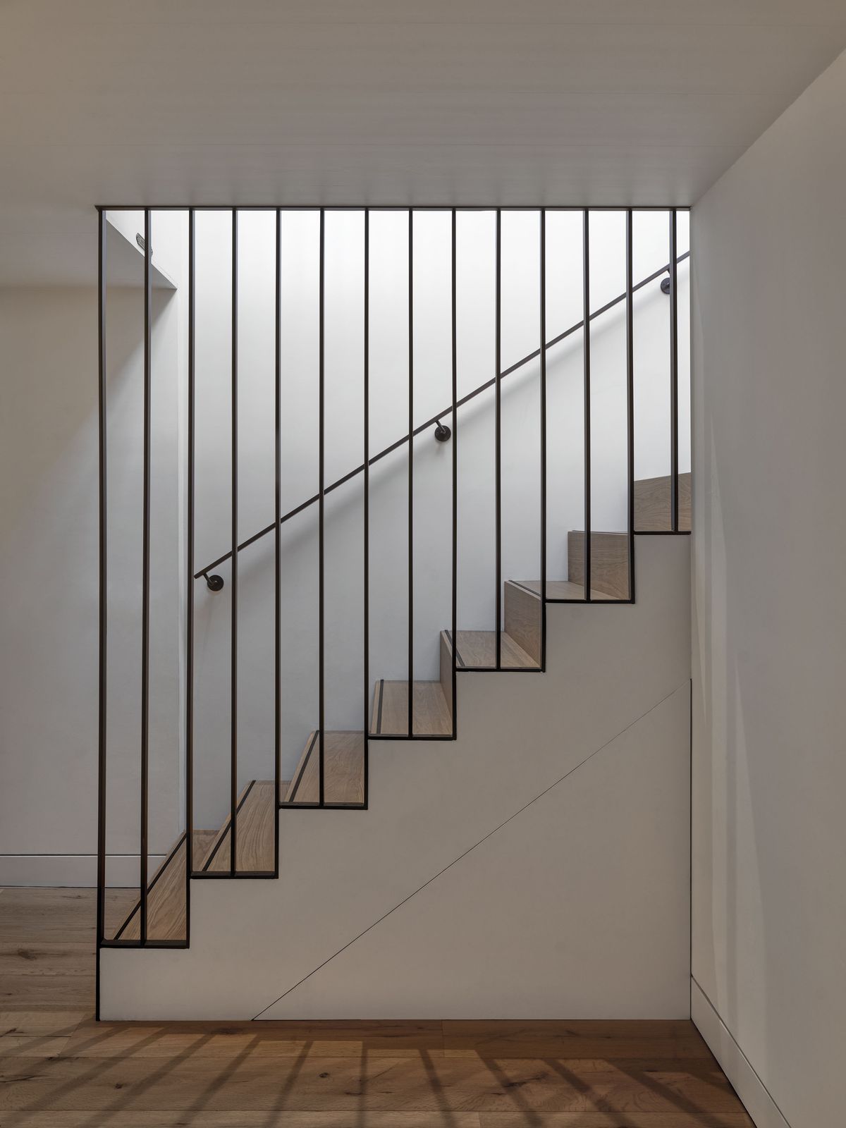 Open trap met eiken treden en een balustrade van zwarte stalen spijlen