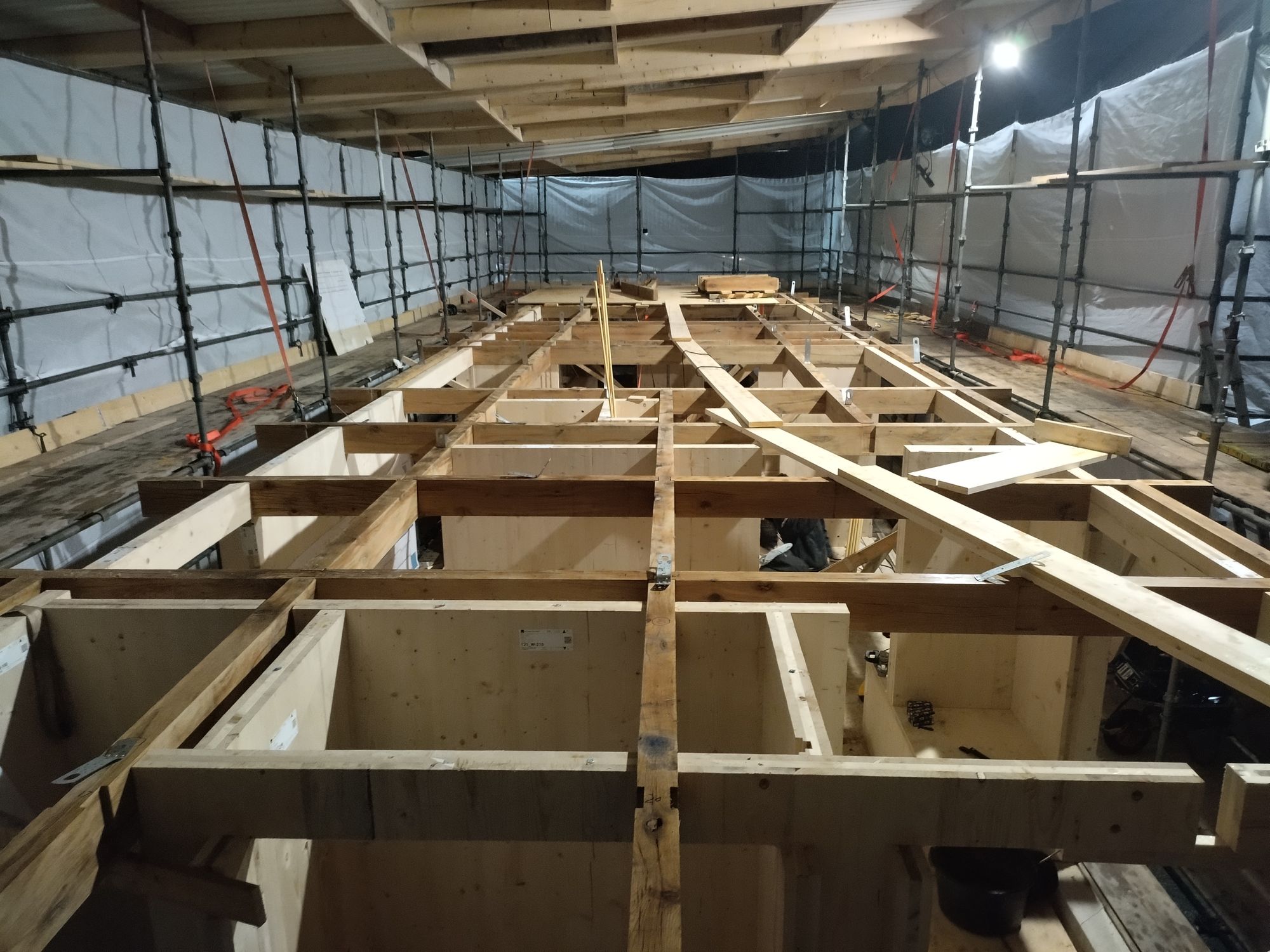 Houten balkenstructuur van een drijvende woning in aanbouw, in de bouwtent op de werf