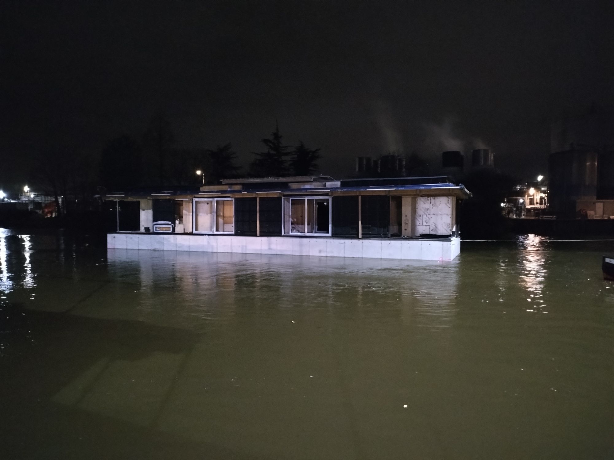 Drijvende woning in het donker op het water naast de werf