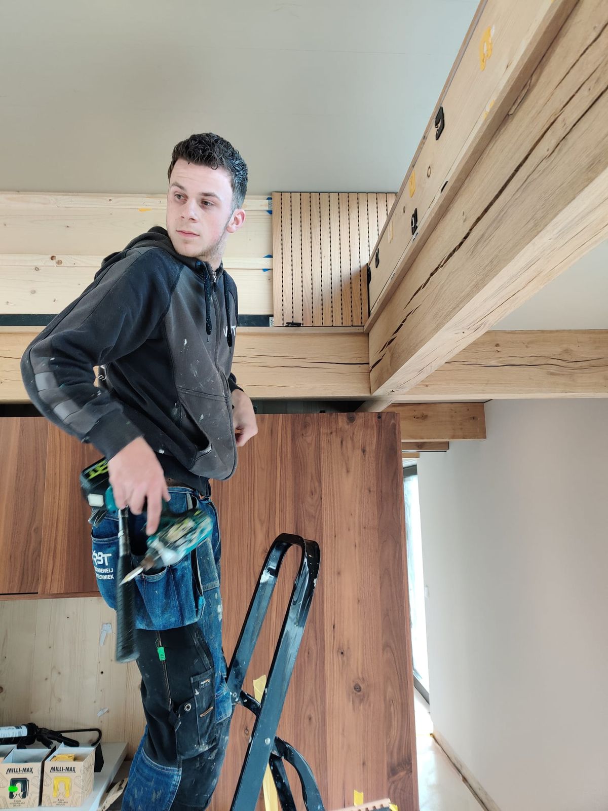 Timmerman op een trap monteert eiken balken in een drijvende woning op de werf